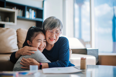 An elderly woman hugging a young child