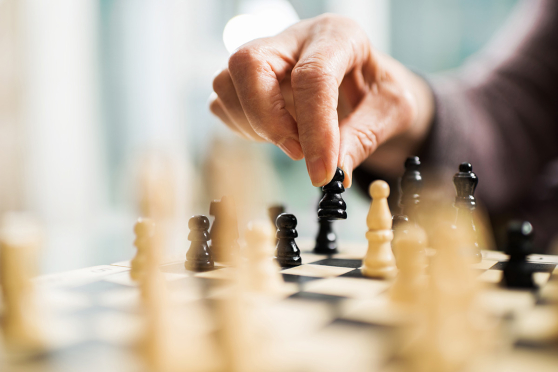 A hand moving a piece on a chess board